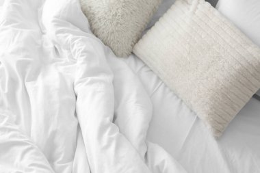 Beyaz battaniyeli yumuşak yastıklar, üst manzara.