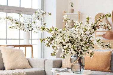 Aydınlık oturma odasındaki masada çiçekli bir vazo.