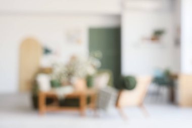 Yeşil kanepesi, koltuğu ve çiçekli dalları olan bulanık bir oturma odası.