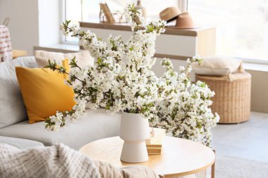 Oturma odasındaki masanın üzerinde çiçek açan bir vazo.