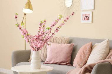 Oturma odasındaki masada pembe çiçekli bir vazo.