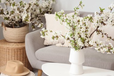 Aydınlık oturma odasındaki masada çiçekli bir vazo.