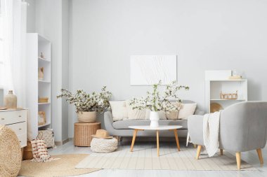 Koltuğu, koltuğu ve çiçekli dalları olan aydınlık oturma odasının içinde.