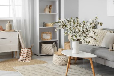 Kanepesi ve çiçekli dallarıyla aydınlık oturma odasının içinde.