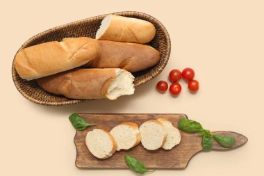 Tahta ve hasır kâse taze baget, fesleğen ve bej arka planda kiraz domatesli.