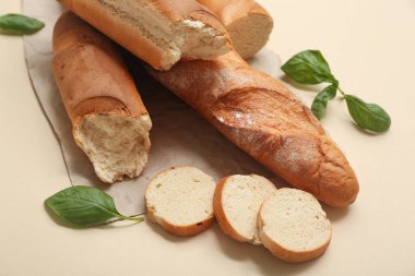 Taze baget ekmekli kağıt ve bej arka planda fesleğen, yakın plan