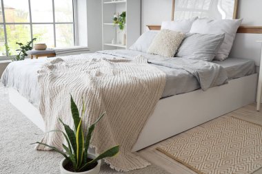 Konforlu yatak odası, battaniye ve çiçekli.