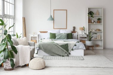 Konforlu yatağı, raf ünitesi ve çiçekleri olan hafif yatak odasının içi.