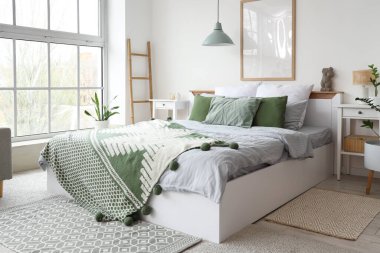 Konforlu yatağı, büyük penceresi ve çiçekleri olan aydınlık yatak odasının içi