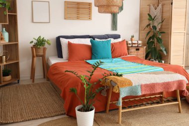 Şık bir yatak odası, rahat bir yatak, ev bitkileri ve ahşap mobilyalar.