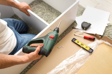 Evinde sondaj rafı montajı yapan genç bir adam var.