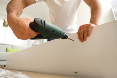 Evinde sondaj rafı montajı yapan genç adam, yakın plan.