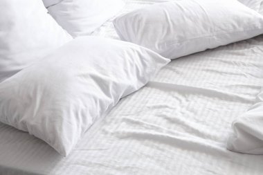 Yatak odasında yumuşak yastıkları ve buruşuk battaniyesi olan rahat bir yatak.