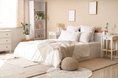 Işıl ışıl yatak odasının içinde rahat yatak odası, puf ve komodin.