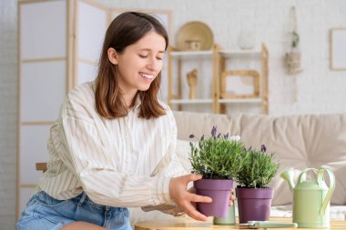 Genç kadın evdeki masaya lavanta çiçeği koyuyor.