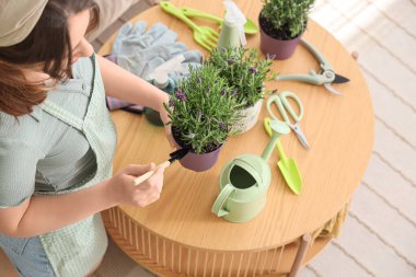 Evinde kürek ve lavanta çiçekleri olan genç bir kadın.