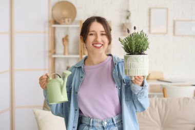 Evde lavanta çiçekleri ve sulama kutusu olan genç bir kadın var.