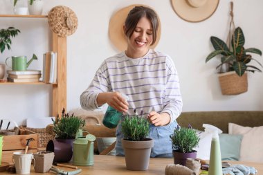 Evdeki lavanta çiçeklerine su püskürten genç bir kadın.