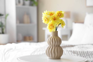 Vazo dolusu narsisli çiçek yatak odasındaki komodinin üstünde, yakın plan.