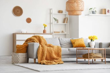 Gri kanepesi ve kahve masasında güzel narsisli çiçekleri olan şık bir oturma odası.