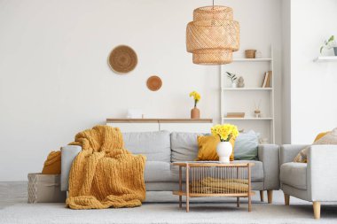 Gri kanepeleri ve kahve masasında güzel narsisli çiçekleri olan şık bir oturma odası.