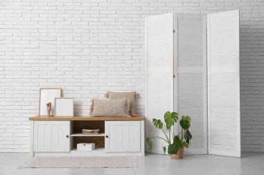 Katlanan ekran, bank ve palmiye bitkisi olan odanın içi