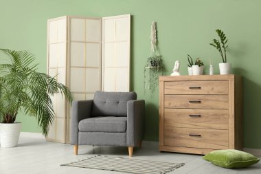 Katlanır ekran, koltuk ve yeşil bitkilerle oturma odasının içi