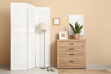 Beyaz katlanır ekran, lamba ve klozet olan odanın içi