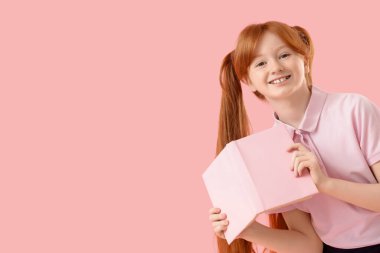 Pembe arka plan kitabı olan kızıl saçlı tatlı bir kız.