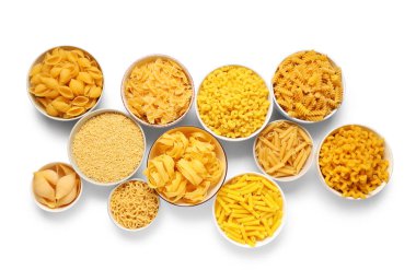 Beyaz arka planda farklı tipte çiğ makarna olan kaseler