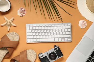 Turuncu arka planda klavyesi, kamerası ve plaj dekoru olan dizüstü bilgisayar