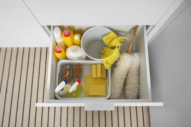 Modern mutfakta temizlik malzemeleri, sepet ve kova dolu çekmece.