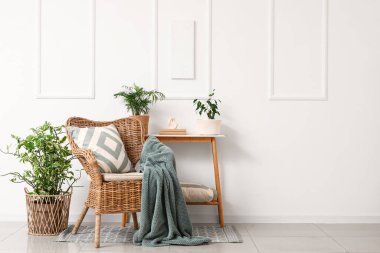 Hasır koltuk, masa ve bitkilerle dolu oturma odasının içinde.