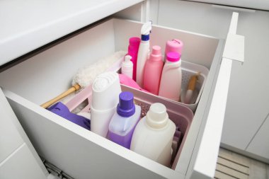 Modern mutfakta temizlik malzemeleri ve sepetlerle dolu çekmeceler.