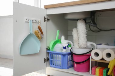 Mutfakta lavabonun altında farklı temizlik malzemeleri ve kağıt havlular olan sepetler ve kova.