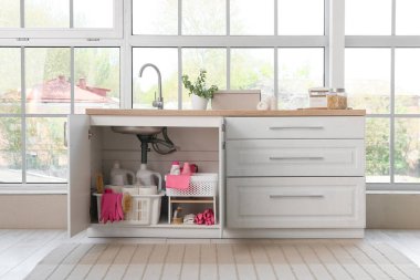 Mutfakta lavabonun altında farklı temizlik malzemeleri ve kağıt havlular olan sepetler.