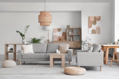 Rahat gri koltukları, kahve masası ve çiçekleri olan şık bir oturma odası.