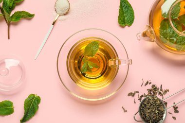 Pembe arka planda bir fincan taze nane çayı.