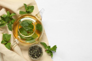 Hafif ahşap zemin üzerinde çaydanlık ve nane, üst görünüm