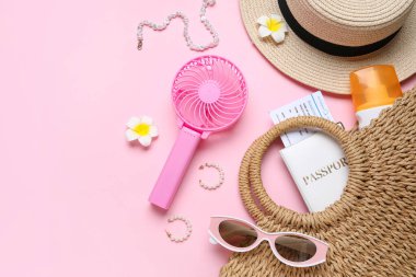 Kadın yaz aksesuarları, pasaport, bilet ve pembe arka planda kısa mesaj için yeri olan mini vantilatör.