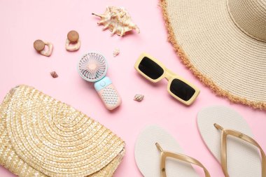 Kadın aksesuarları ve pembe arka planda mini fanı olan bir çanta.