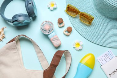 İçinde kadın aksesuarları, kulaklıklar ve mavi arka planda mini vantilatör olan bir çanta.