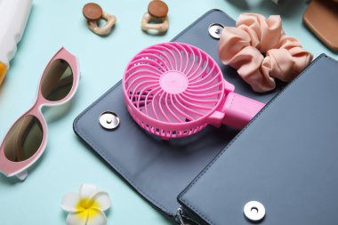 Kadın yaz aksesuarları ve mavi arka planda mini fanı olan bir çanta.