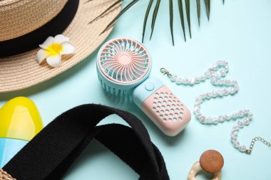 Kadın yaz aksesuarları ve mavi arka planda mini fan.