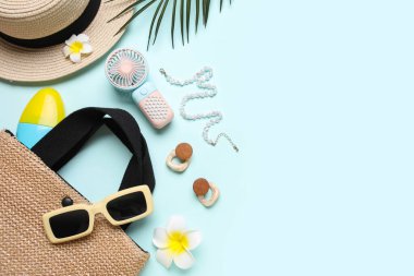 Kadın yaz aksesuarları ve mavi arka planda mini fanı olan bir çanta.