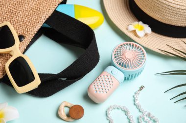 Kadın yaz aksesuarları ve mavi arka planda mini fanı olan bir çanta.