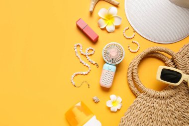 Kadın yaz aksesuarları ve sarı arka planda küçük yelpaze dolu çantalar.