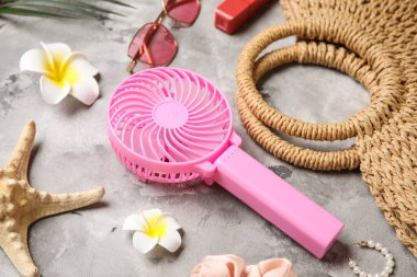 Yaz aksesuarları ve arka planda mini fan olan bir çanta.