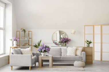 Oturma odasının içinde, vazolarda leylak çiçekleri var.