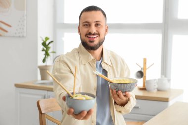 Mutfakta lezzetli ramen yiyen genç adam.